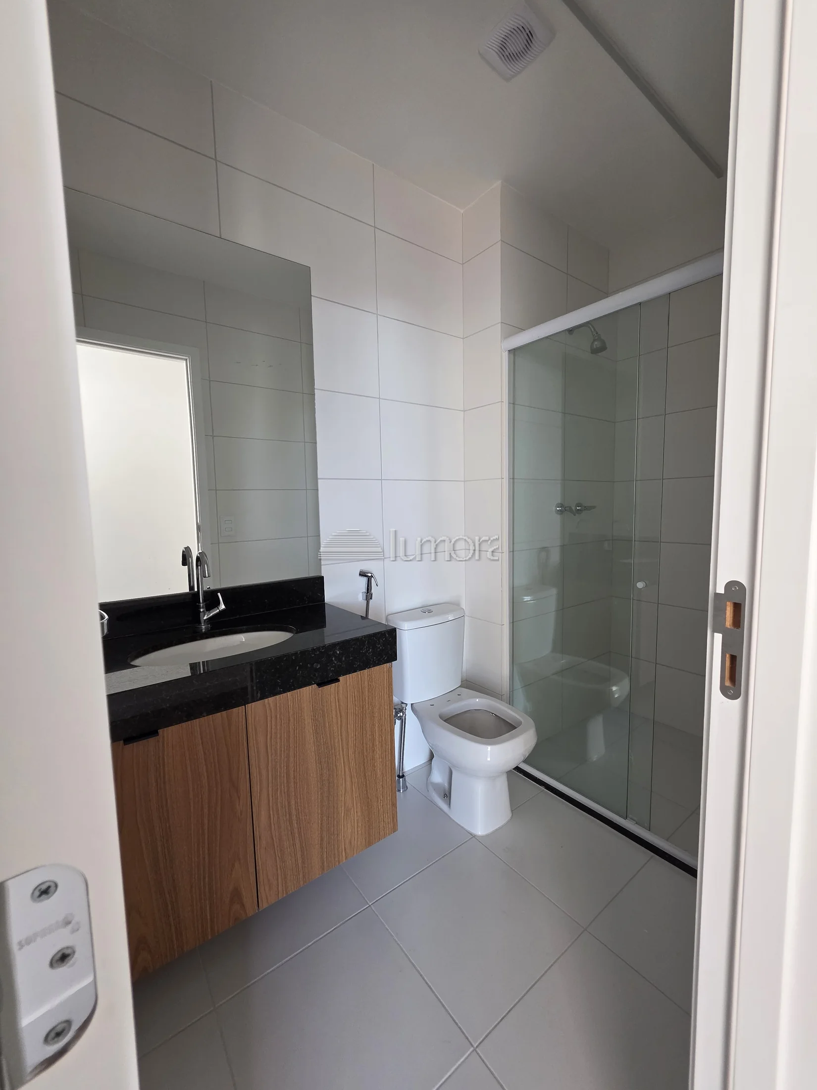 Banheiro do apartamento Torre Evidence com box de vidro e bancada em granito