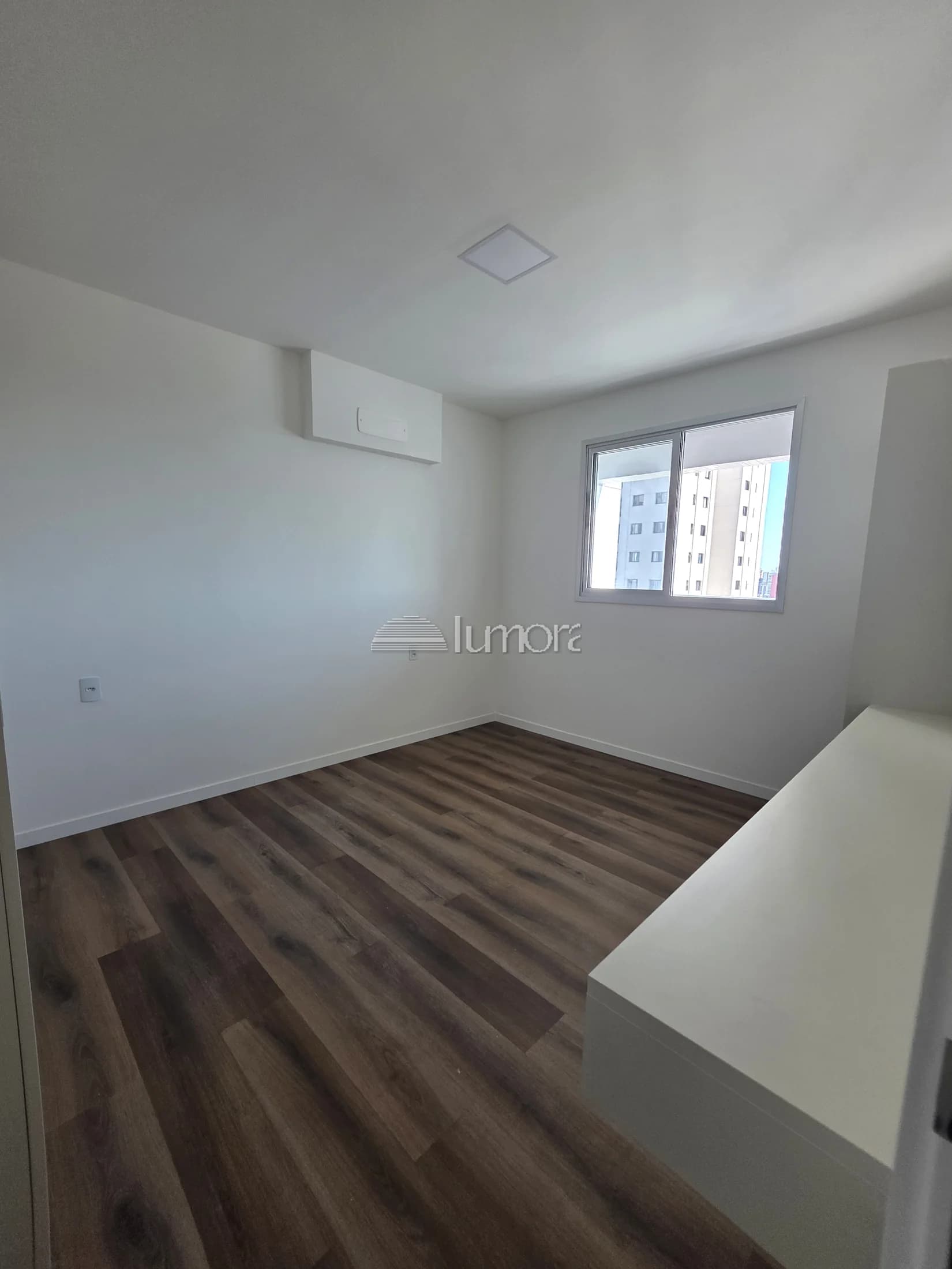 Quarto do apartamento Torre Evidence com iluminação natural e piso amadeirado