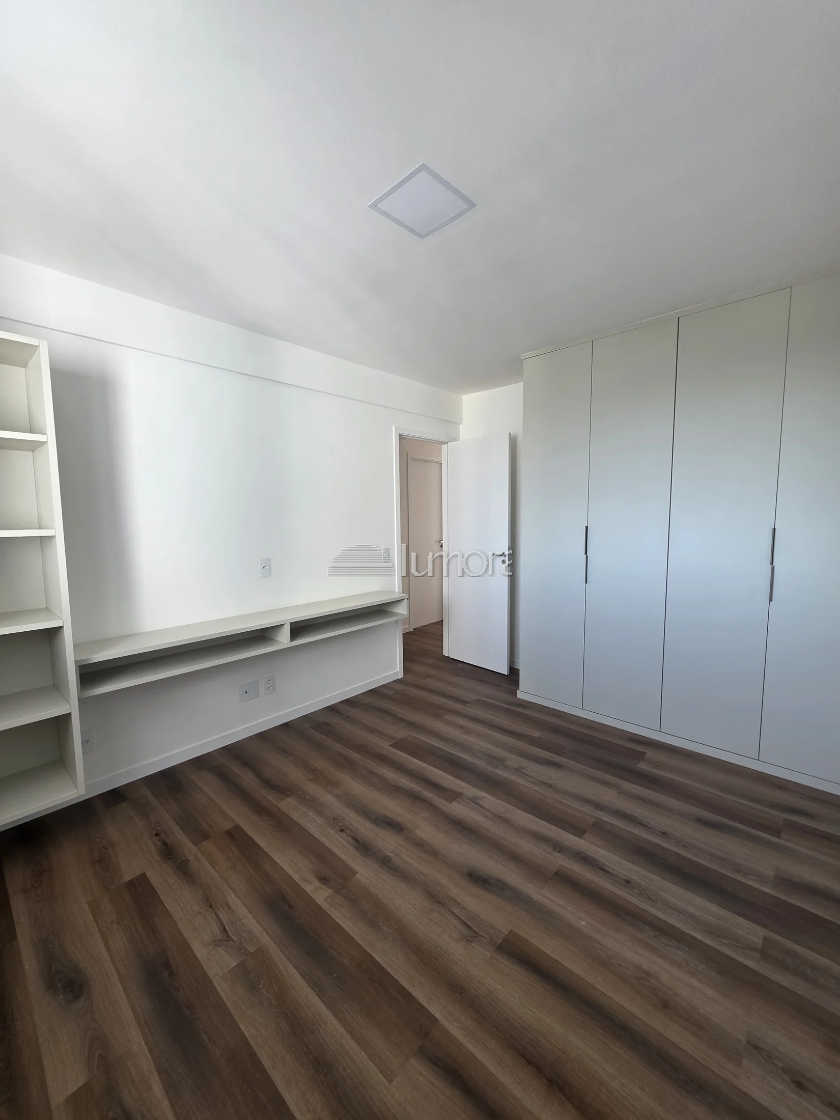 Quarto do apartamento Torre Evidence com móveis planejados, bancada e piso amadeirado